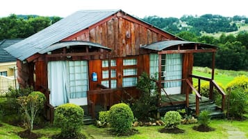 Situated in a lush landscape, this cabin features a porch with a wooden railing and steps leading up to the entrance.