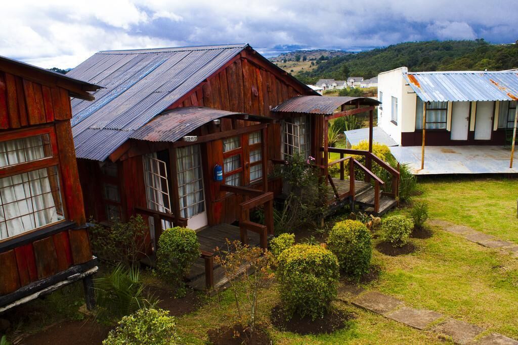Una casa rústica de madera con techo de metal, un porche de madera y un pequeño jardín.