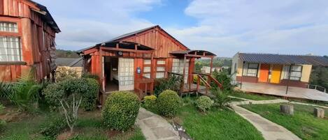 Una cabaña rústica de madera con un porche y una estructura pequeña adosada.