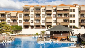 Een hotel met een zwembad, terras en balkons.