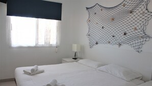 A neatly made bed with two rolled towels, a bedside lamp, and a wall art piece. - Luminoso apartamento con vistas al mar. wifi (Callao Salvaje)