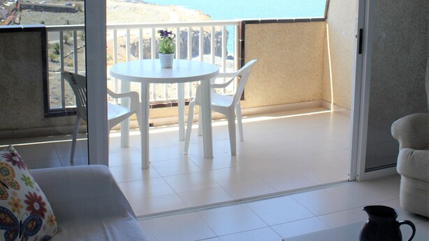 A balcony with a white table and chairs, a white sofa, and a view of the sea. - Luminoso apartamento con vistas al mar. wifi (Callao Salvaje)