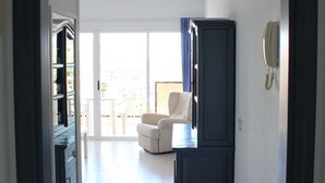 A hallway leading to a living area with a white sofa, a dark cabinet, and a phone on the wall. - Luminoso apartamento con vistas al mar. wifi (Callao Salvaje)