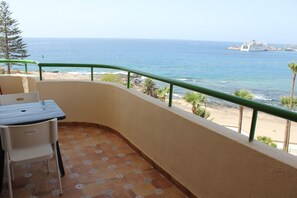 Un balcon avec vue sur la mer, une table, des chaises et une rambarde.