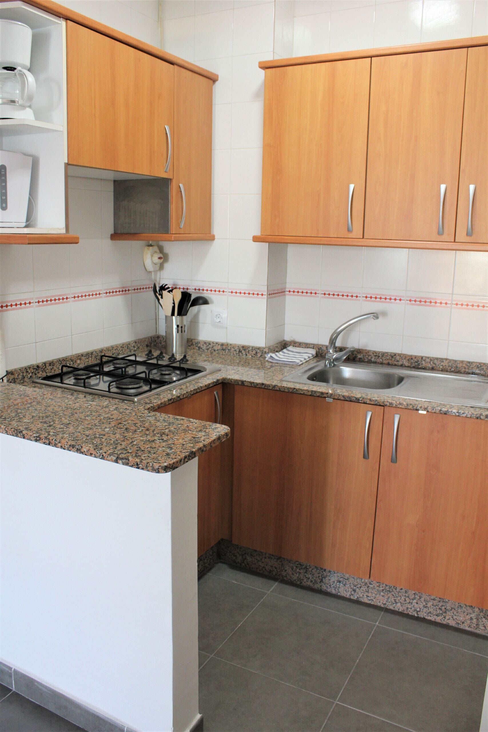 Una cocina con armarios de madera, encimera de granito, estufa a gas y un lavabo.