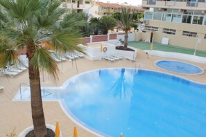 A swimming pool with lounge chairs and palm trees.