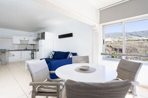 A modern kitchen with white cabinets and a blue sofa in the living area.
