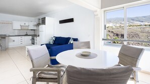 A modern kitchen with white cabinets and a blue sofa in the living area. - Tranquilidad, playa y vistas al mar (Callao Salvaje)