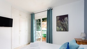 Un dormitorio con cama, televisor de pantalla plana, un cuadro y vistas al exterior.