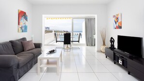 A modern living room with a grey sofa, a white coffee table, a flat-screen TV, and abstract wall art. - Fabuloso apartamento con magnificas vistas al mar (Callao Salvaje)