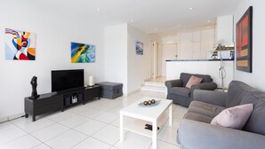 A modern living room with a flat-screen TV, grey sofas, a white coffee table, and abstract art on the walls. - Fabuloso apartamento con magnificas vistas al mar (Callao Salvaje)