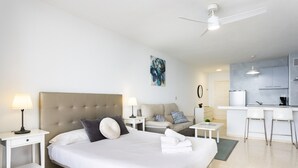 Una habitación de hotel moderna con una cama grande, un sofá, un escritorio y una kitchenette.
