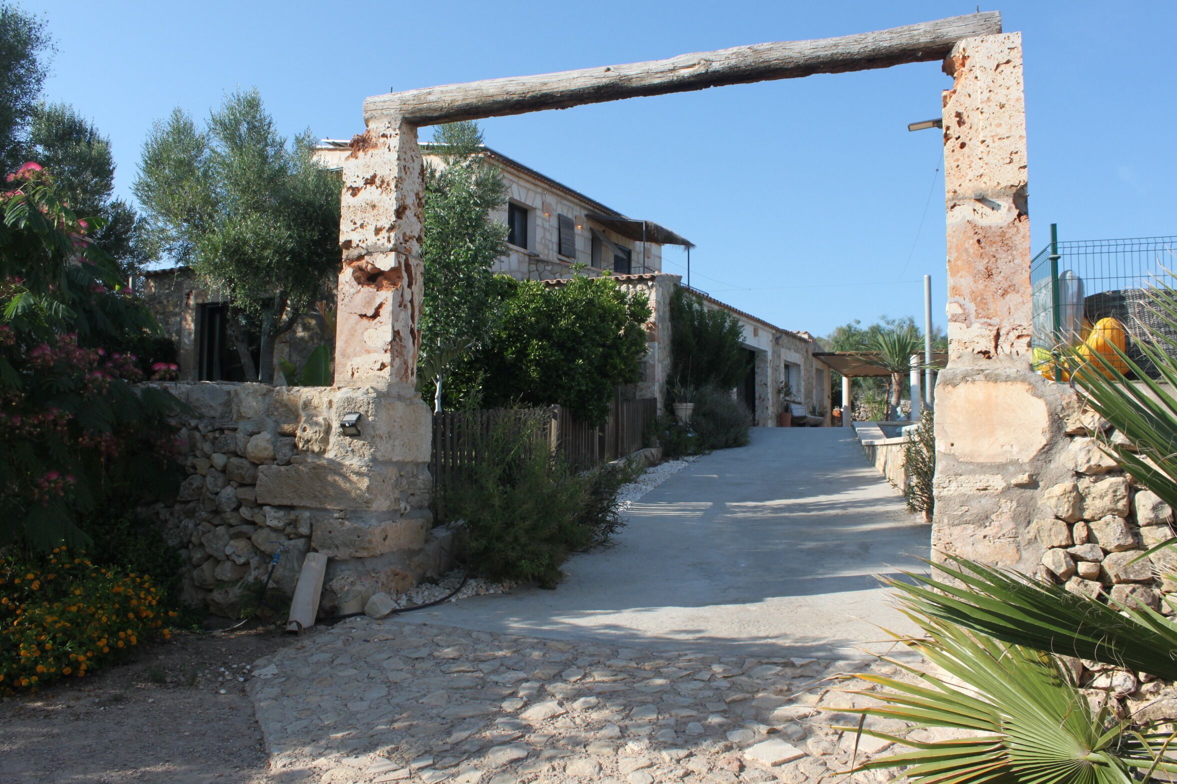 A stone pathway leading to a rustic building with a wooden archway.