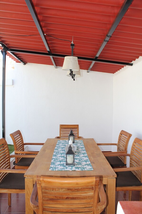 Uma mesa de jantar de madeira com quatro cadeiras, uma toalha e um lustre.