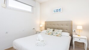 Ein Schlafzimmer mit einem Bett, zwei Nachttischen, einem Fenster und einem an der Wand hängenden Bild.