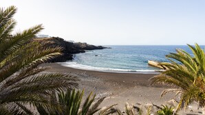 Ein Küstenstrand mit Felsformationen und freiem Blick auf das Meer.