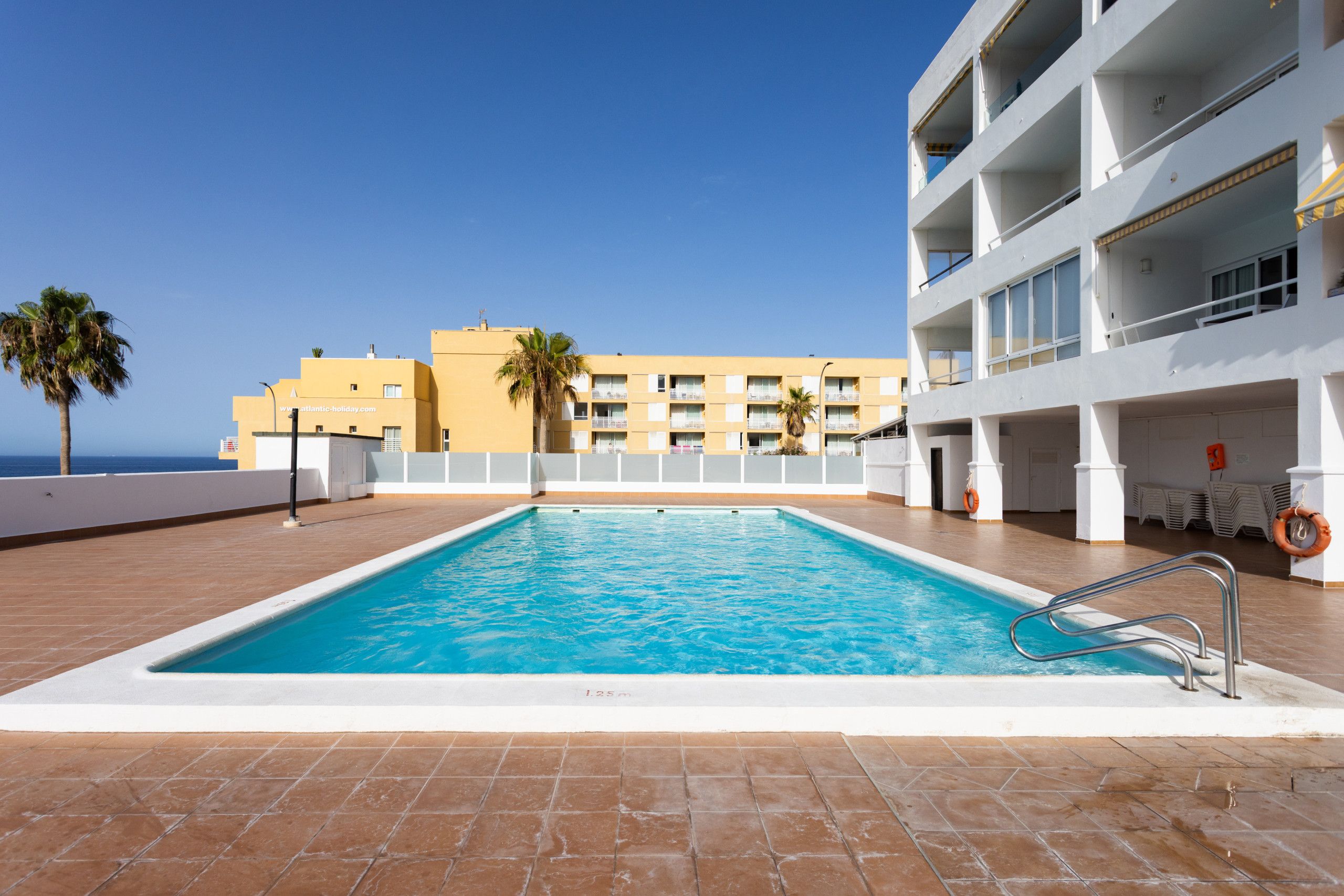 A swimming pool with a clear blue water surface, surrounded by a tiled deck.
