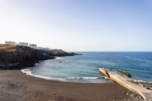 A coastal beach with a concrete walkway, rocky shoreline, and buildings in the background. - Preciosas vistas, playa 200m, WIFI (Callao Salvaje)