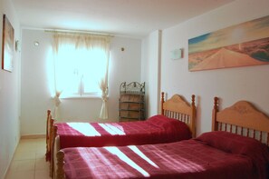 A room with two wooden beds, a window with curtains, a wicker chest of drawers, and a landscape painting on the wall. - 4 Bed Fantastic Apt, Private Pool Close to Golf, Beach and Entertainment (Orihuela Costa)