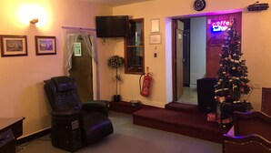 A living room with a leather recliner, a small Christmas tree, and a flat-screen TV mounted on the wall. - Don Valley Hotel (Sheffield)