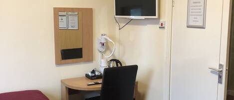 Une chambre d’hôtel avec deux lits simples, un bureau avec une chaise, un téléviseur fixé au mur et une porte avec une pancarte.