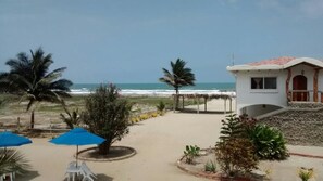 A beachside property with a patio area, palm trees, and a view of the ocean. - Sundown Beach Hotel (Canoa)