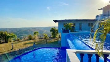 Una piscina con vistas a una casa y montañas al fondo.