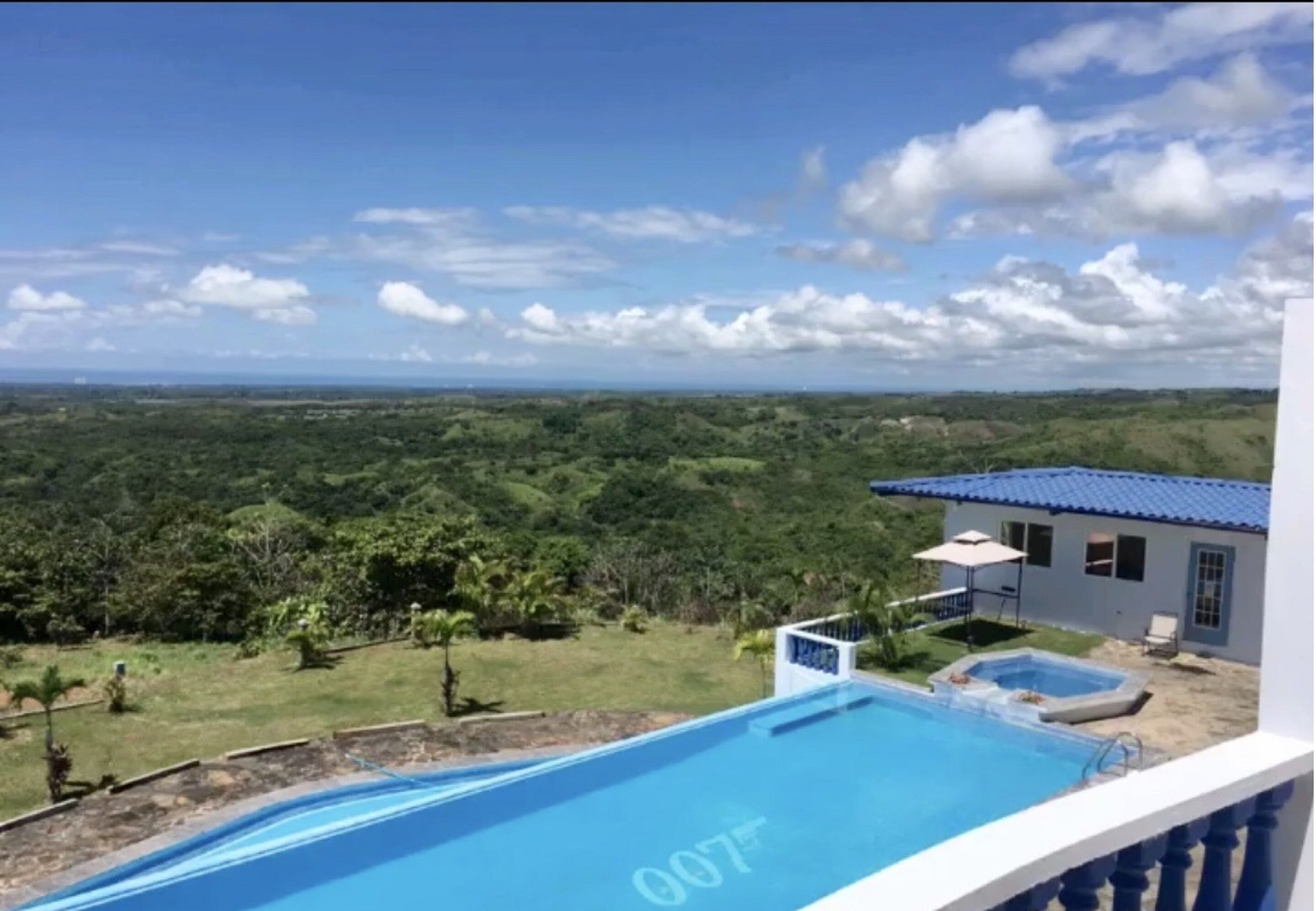 A swimming pool with a view of a lush landscape and a building with a blue roof.