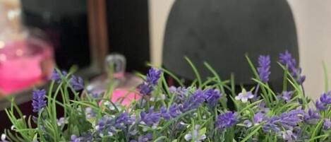 En vit skål fylld med lila blommor, placerad på en träyta.