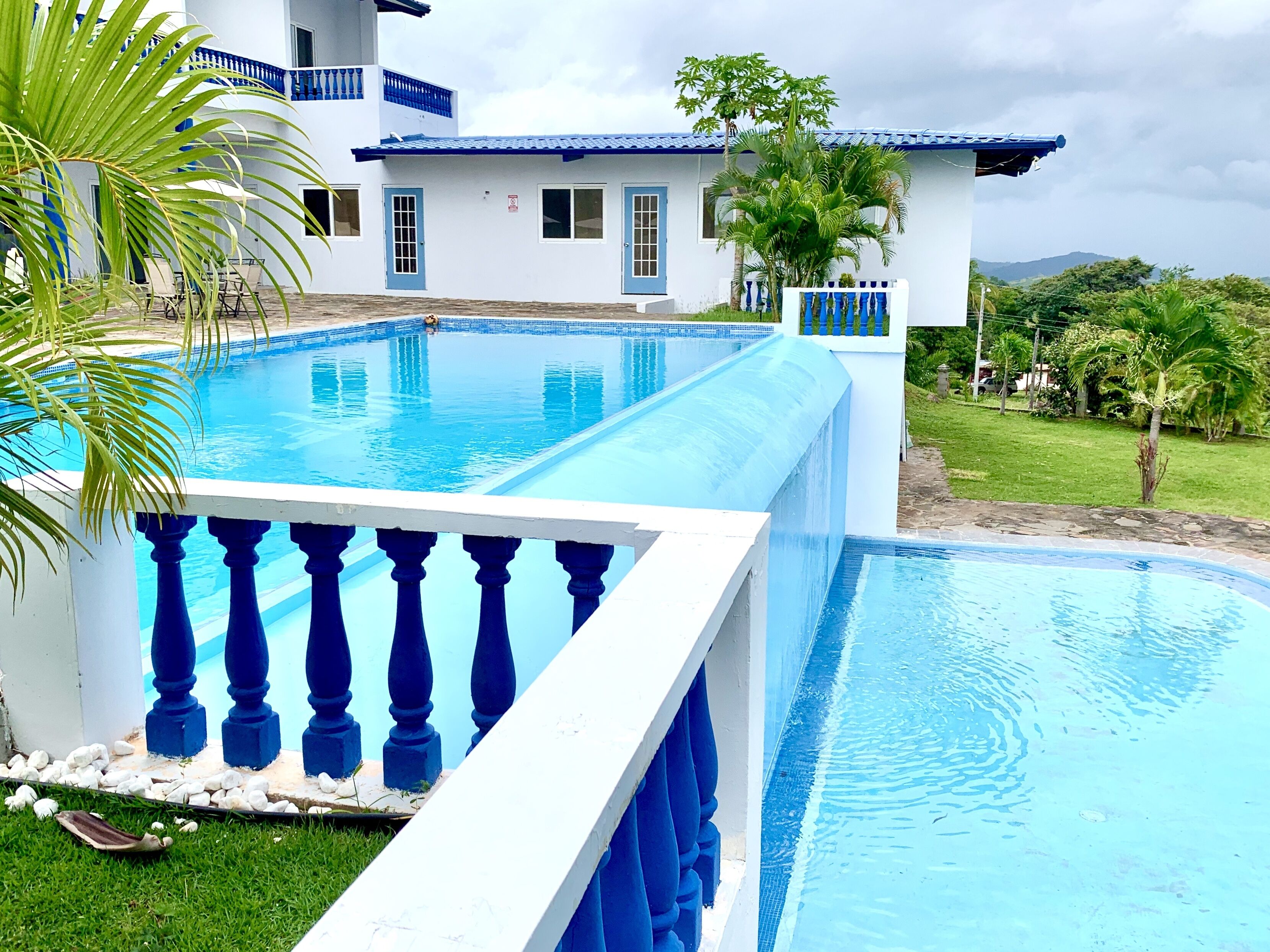 Una amplia piscina con decoración azul y blanca, rodeada por una valla blanca con barandillas azules.
