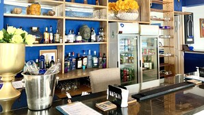 Zona de bar con estantes llenos de botellas de licor, un refrigerador con bebidas y una caja registradora.