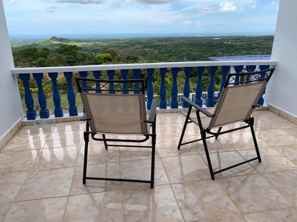 Un balcón con dos sillas y vista a un paisaje verde.