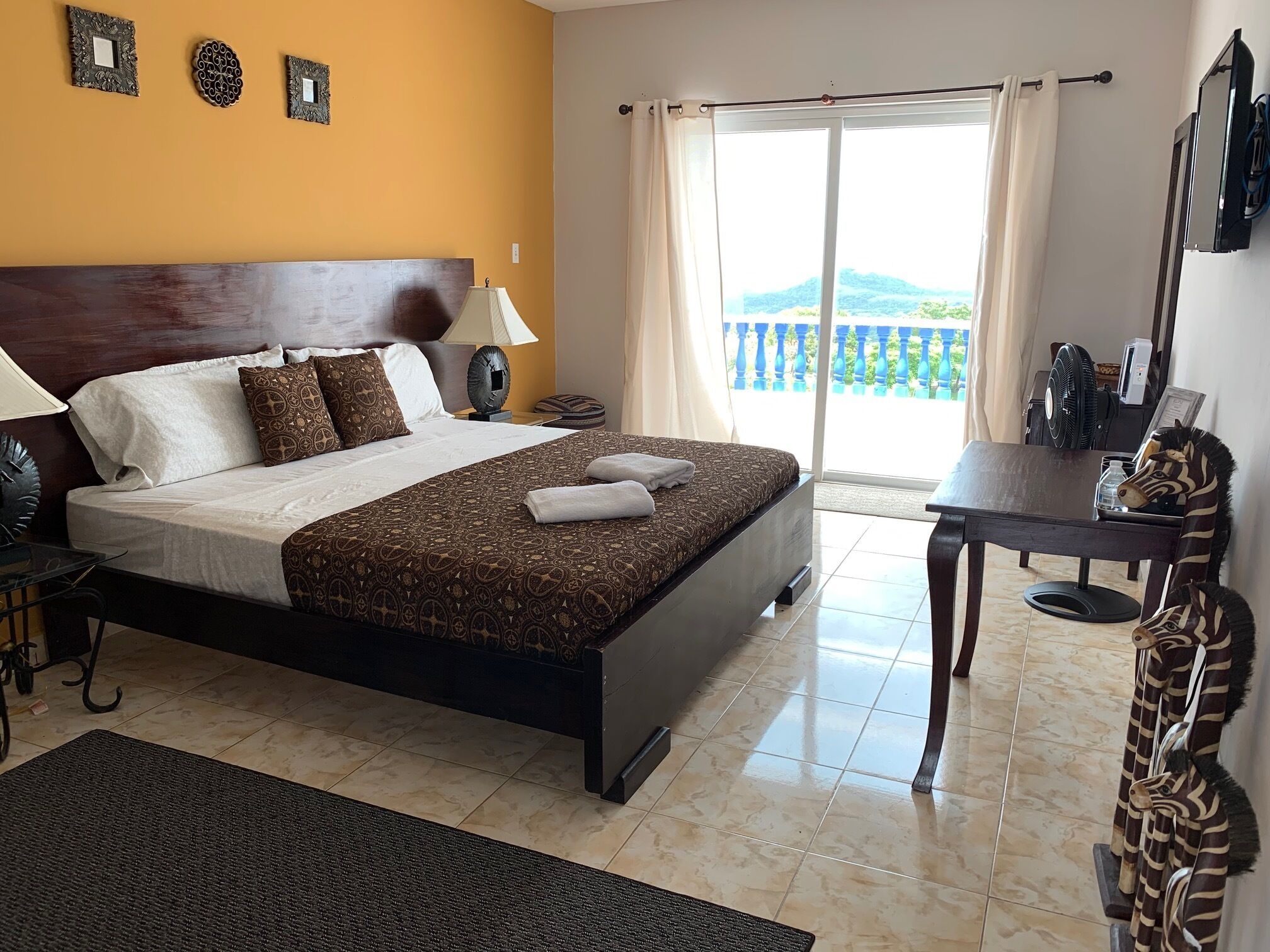 A hotel room with a large bed, a desk, and a view of the outdoors.
