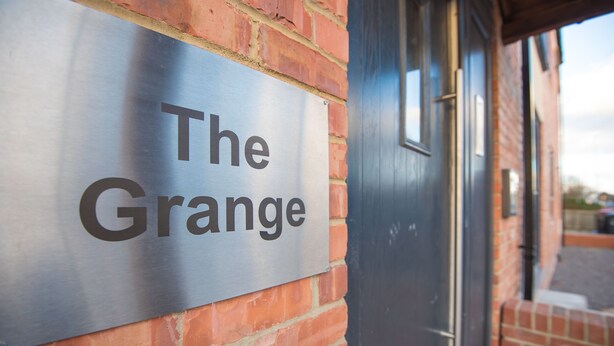 A sign on a brick wall that reads "The Grange."