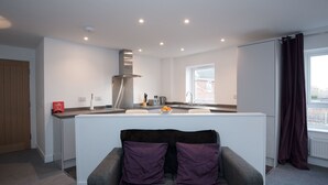 A modern kitchen with a central island, a built-in stove, and a window with curtains.