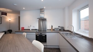 A modern kitchen with a stainless steel range hood, a built-in oven, and a window providing natural light.