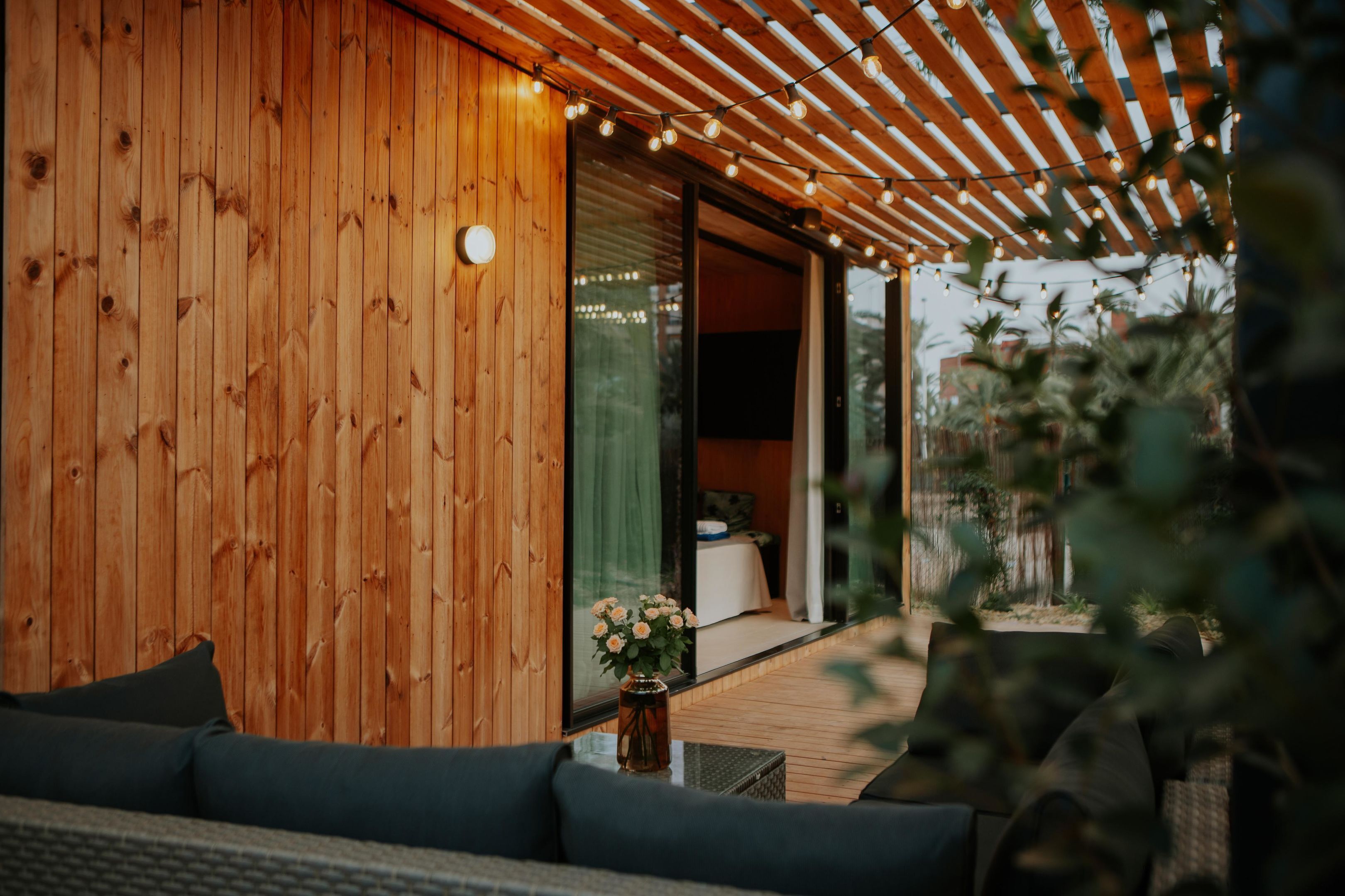 Eine Holzfassade mit einer Schiebetür, die zu einer Terrassenfläche führt.