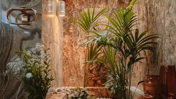 Una habitación con pared de mármol, un banco de madera y plantas en macetas.