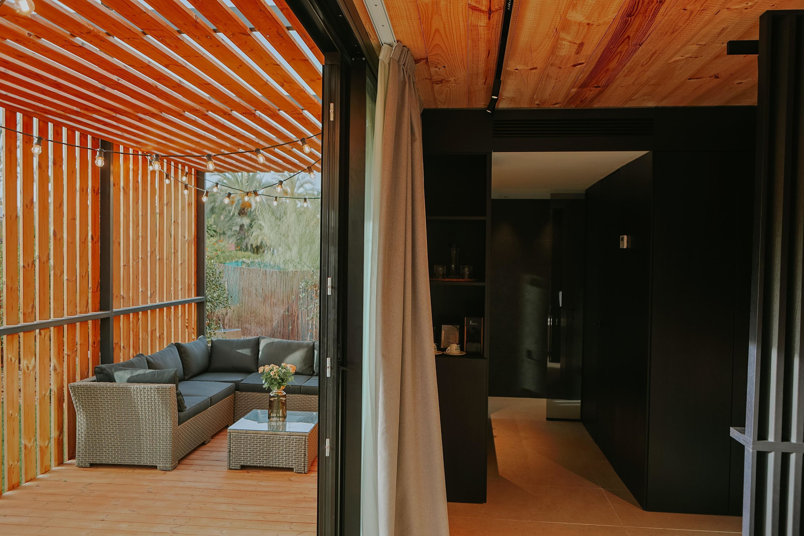 A modern living space with a wooden ceiling, a sectional sofa, a coffee table, and a view of the outdoors.