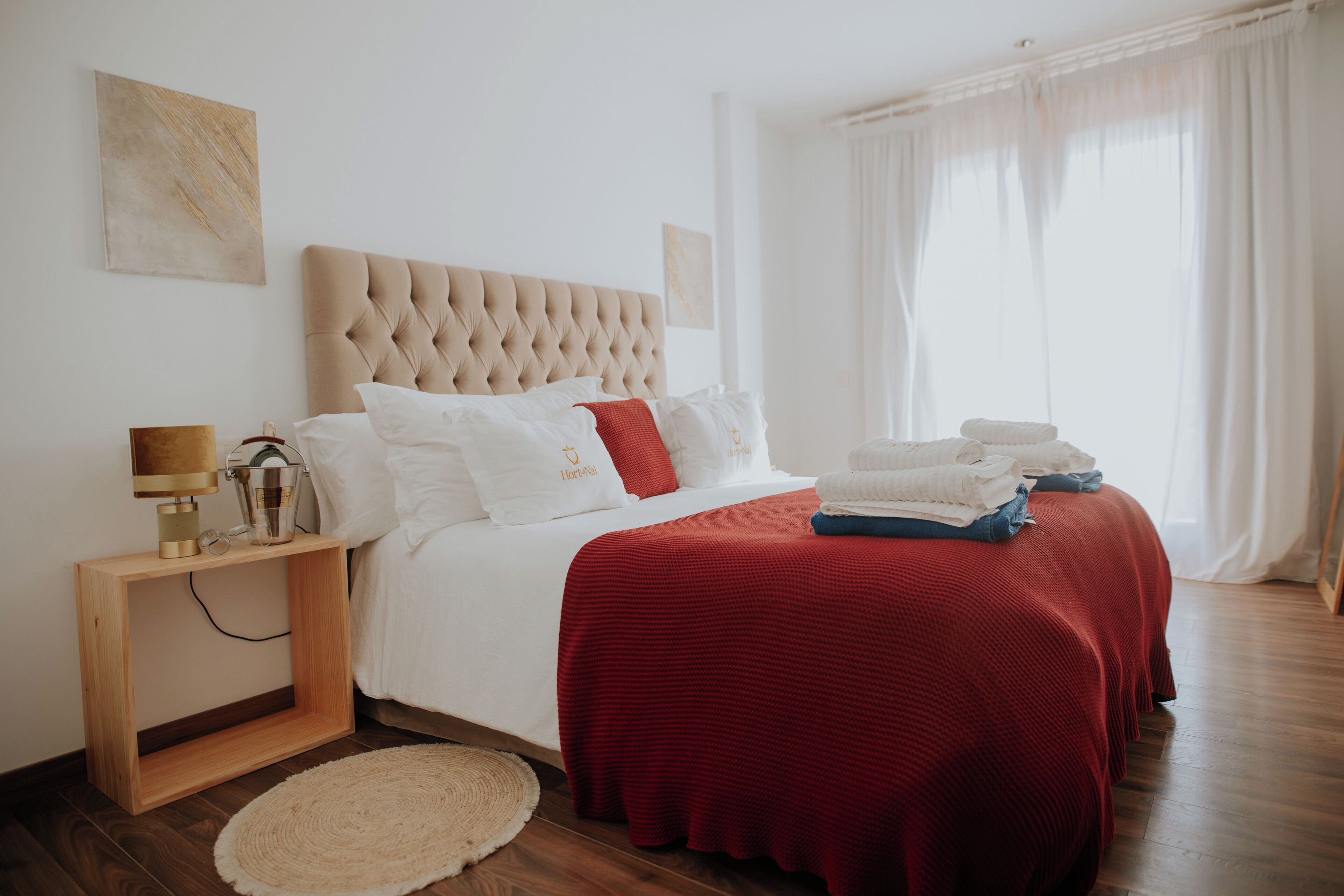 A neatly arranged bedroom with a large bed, a bedside table with a lamp, and a bedside basket.
