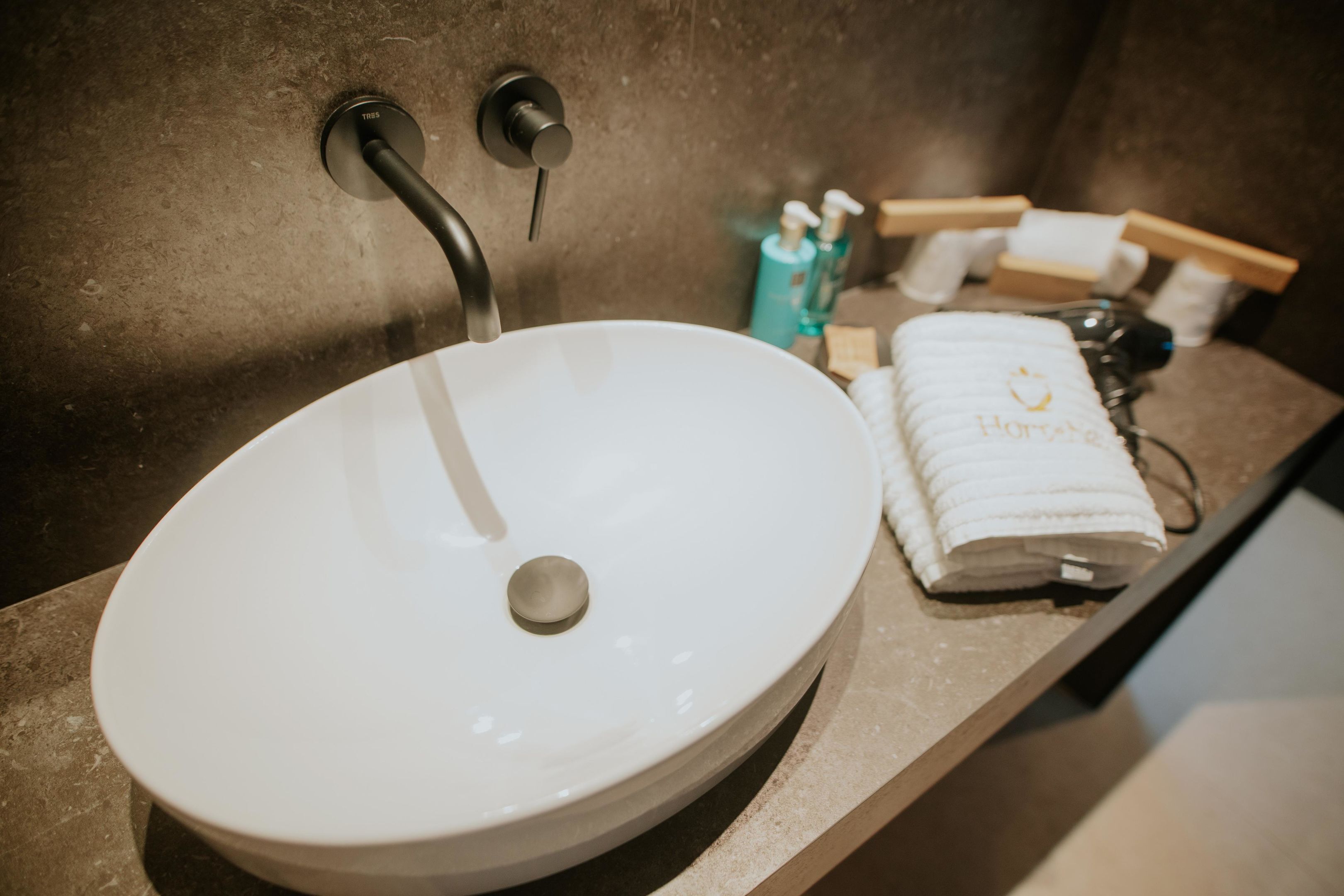 Een badkamer met een wit wastafelmeubel, een handdoek en toiletartikelen op de aanrecht.