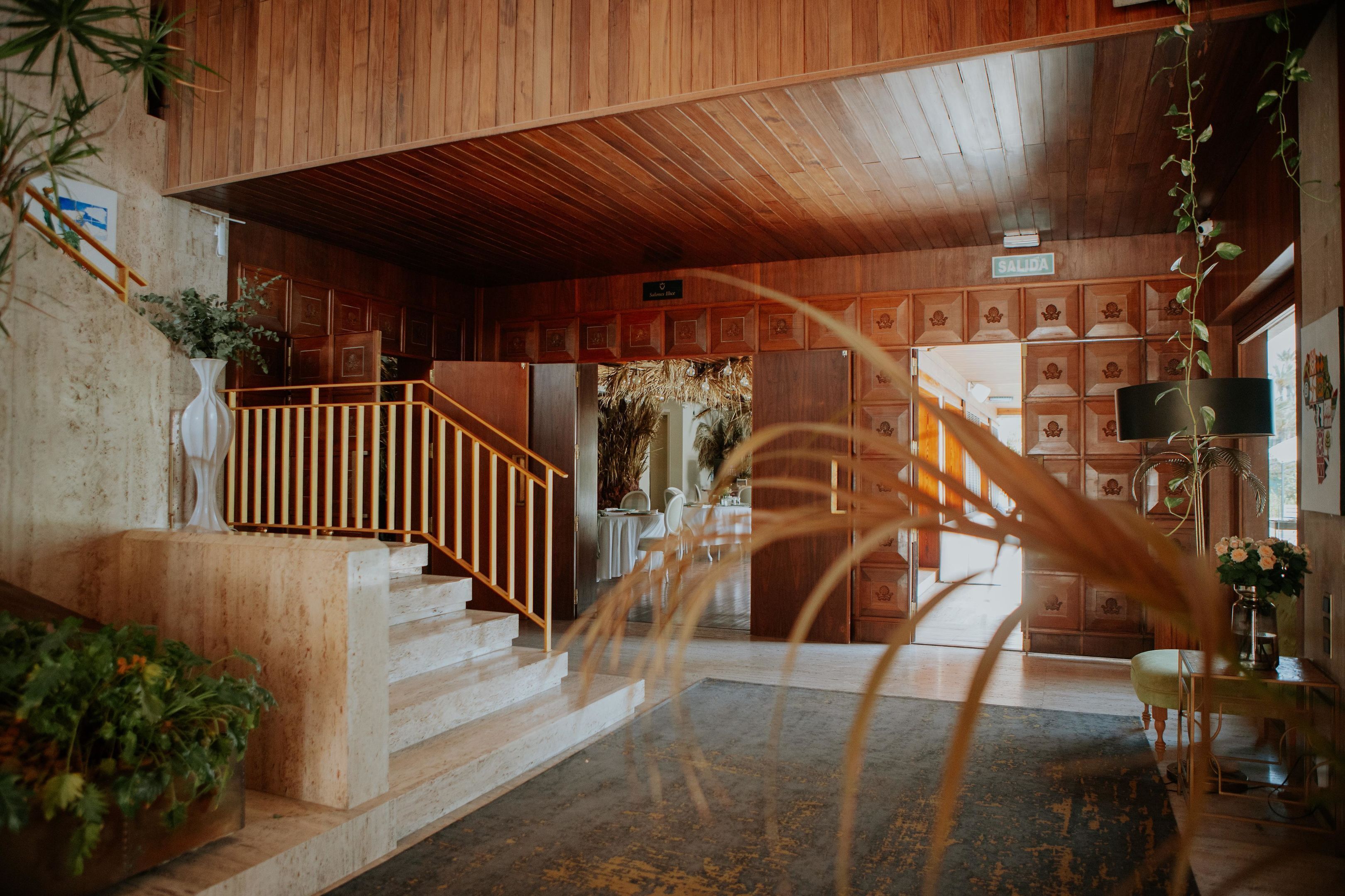 Un interior de madera con una escalera, un mostrador de recepción y un letrero que dice "SALIDA".