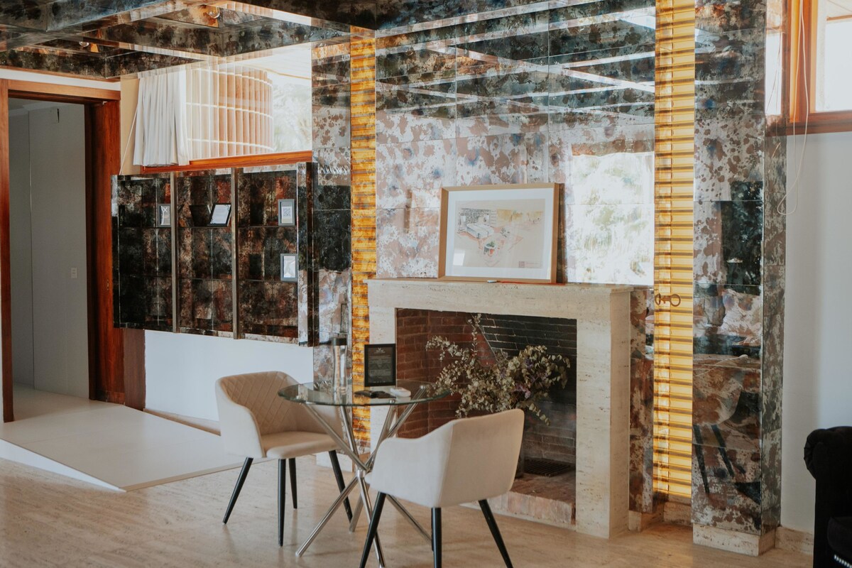 A modern interior with a fireplace, glass table, and chairs.
