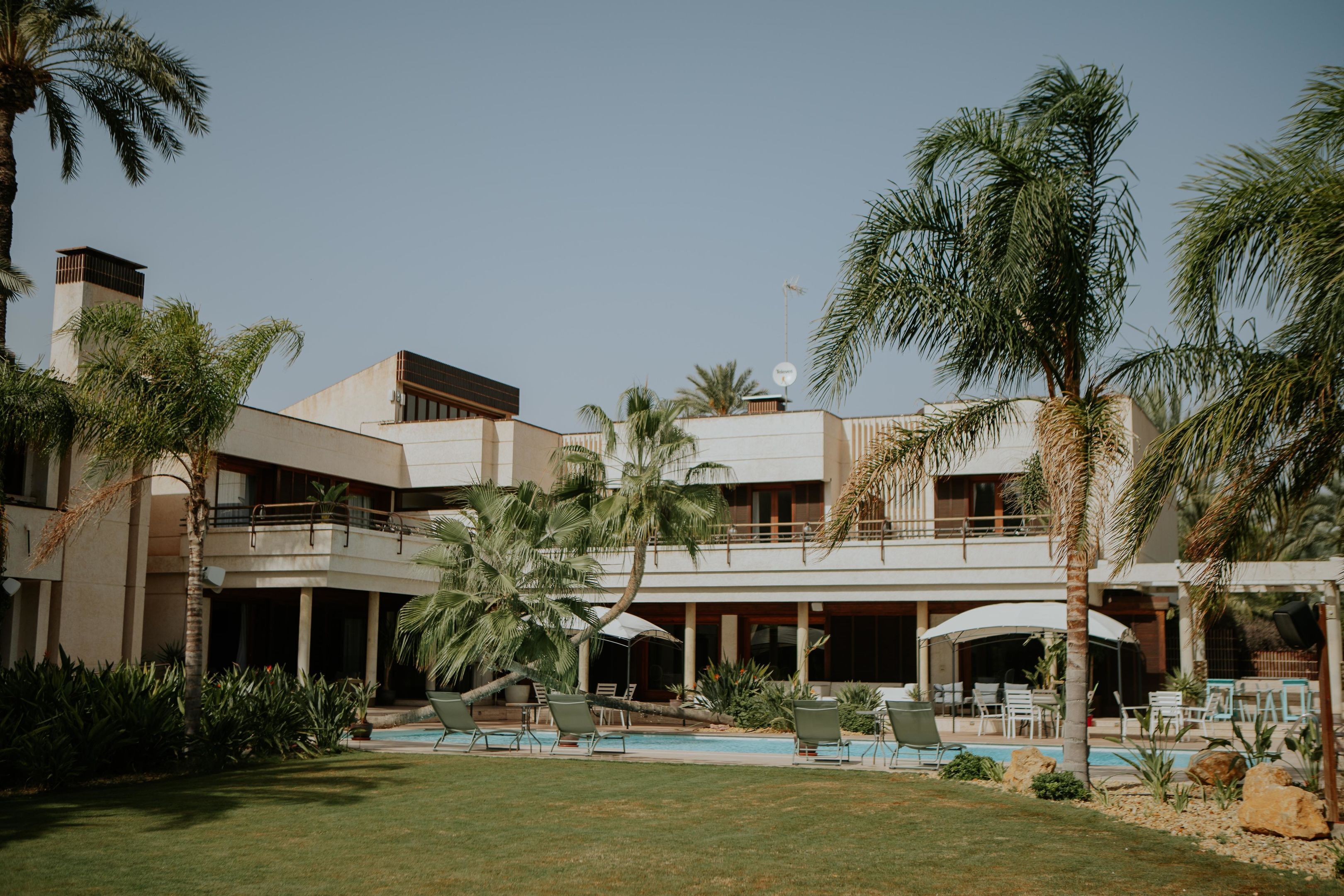 Un resort con piscina, sillones de descanso y palmeras.