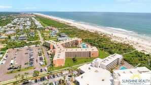 Luchtbeeld van een kusthotel met meerdere gebouwen, een parkeerplaats en een strand.