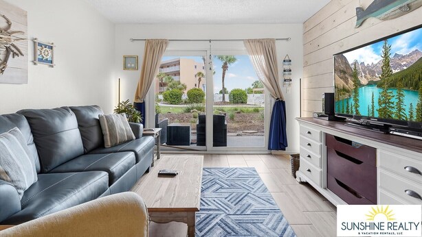 Een moderne woonkamer met een leren bank, een flatscreen-televisie en een schuifdeur naar een balkon.