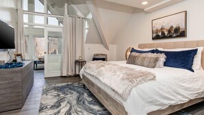 A bedroom with a large bed, a TV, a desk, and a view of the city through a glass door. - PRIME SKI-IN/OUT LOCATION - Park City Mountain Resort Village & Base (Park City)