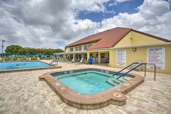 A hotel with a swimming pool, a hot tub, and lounge chairs.