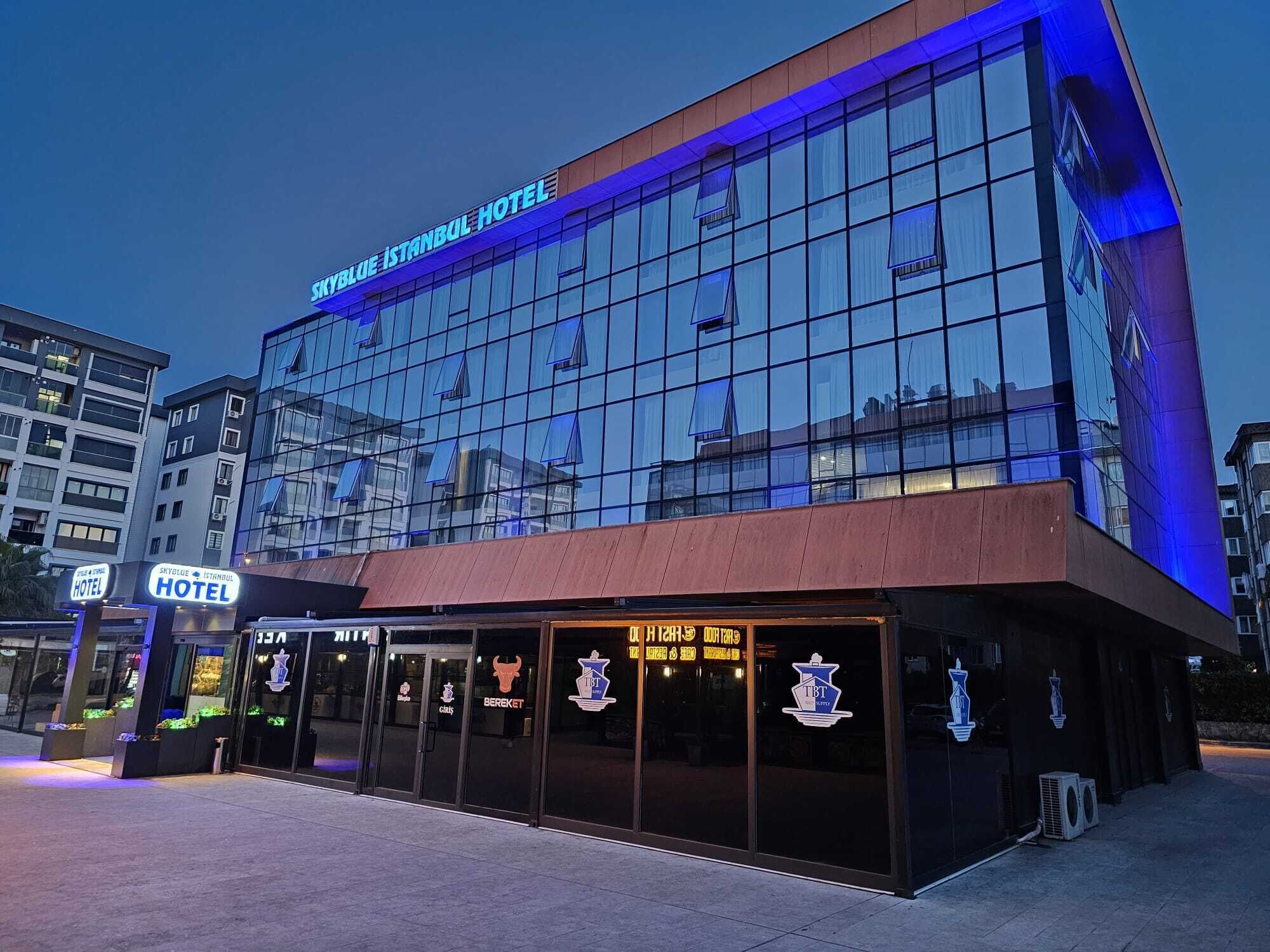 L’extérieur de l’hôtel Skyblue Istanbul se distingue par sa façade moderne en verre et une enseigne indiquant la présence d’un restaurant et d’un bar.