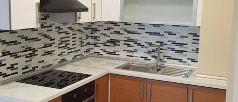 A modern kitchen with a black stove, white cabinets, and a tiled backsplash.